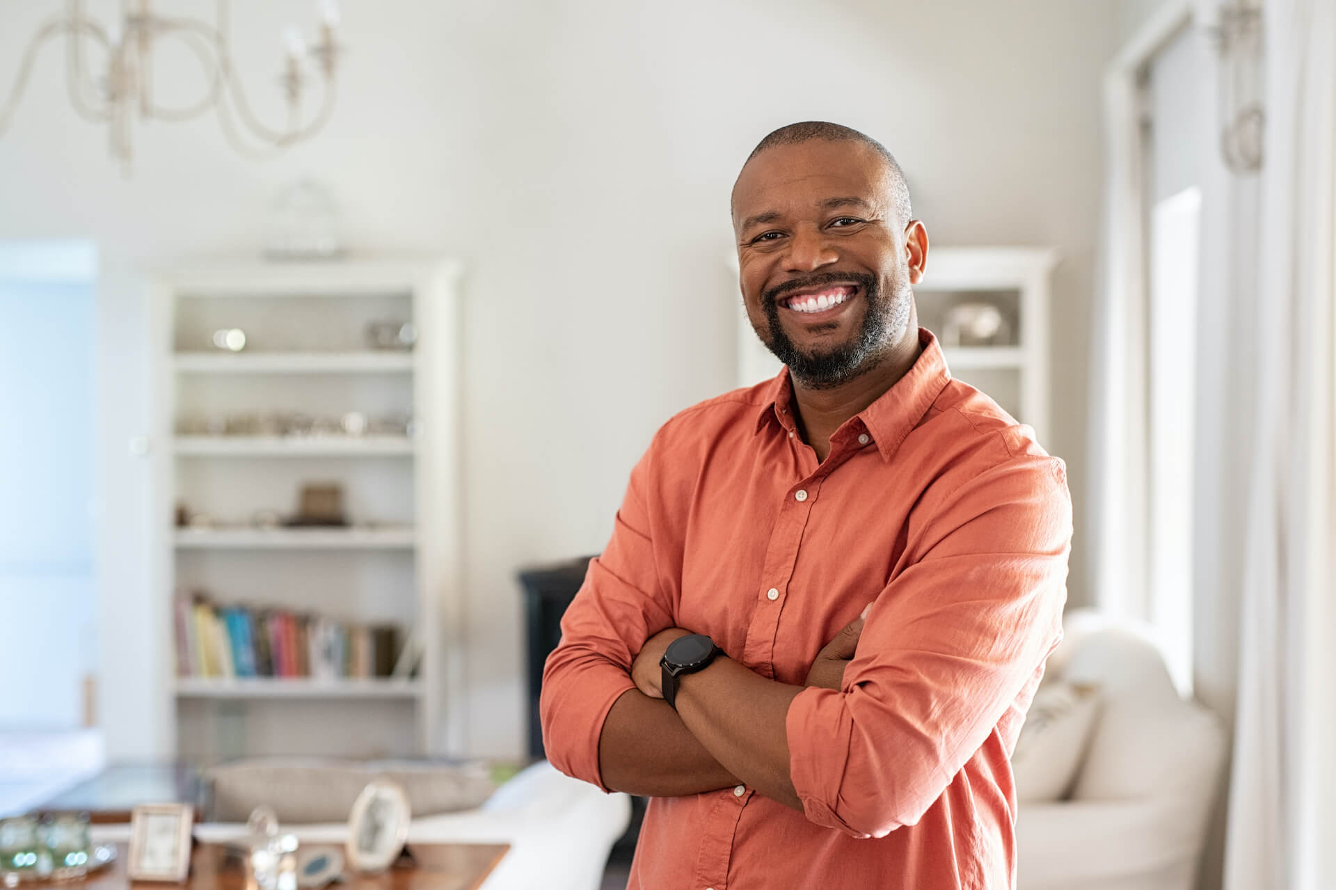 Portrait of smiling mature man with beard standing with crossed arms.